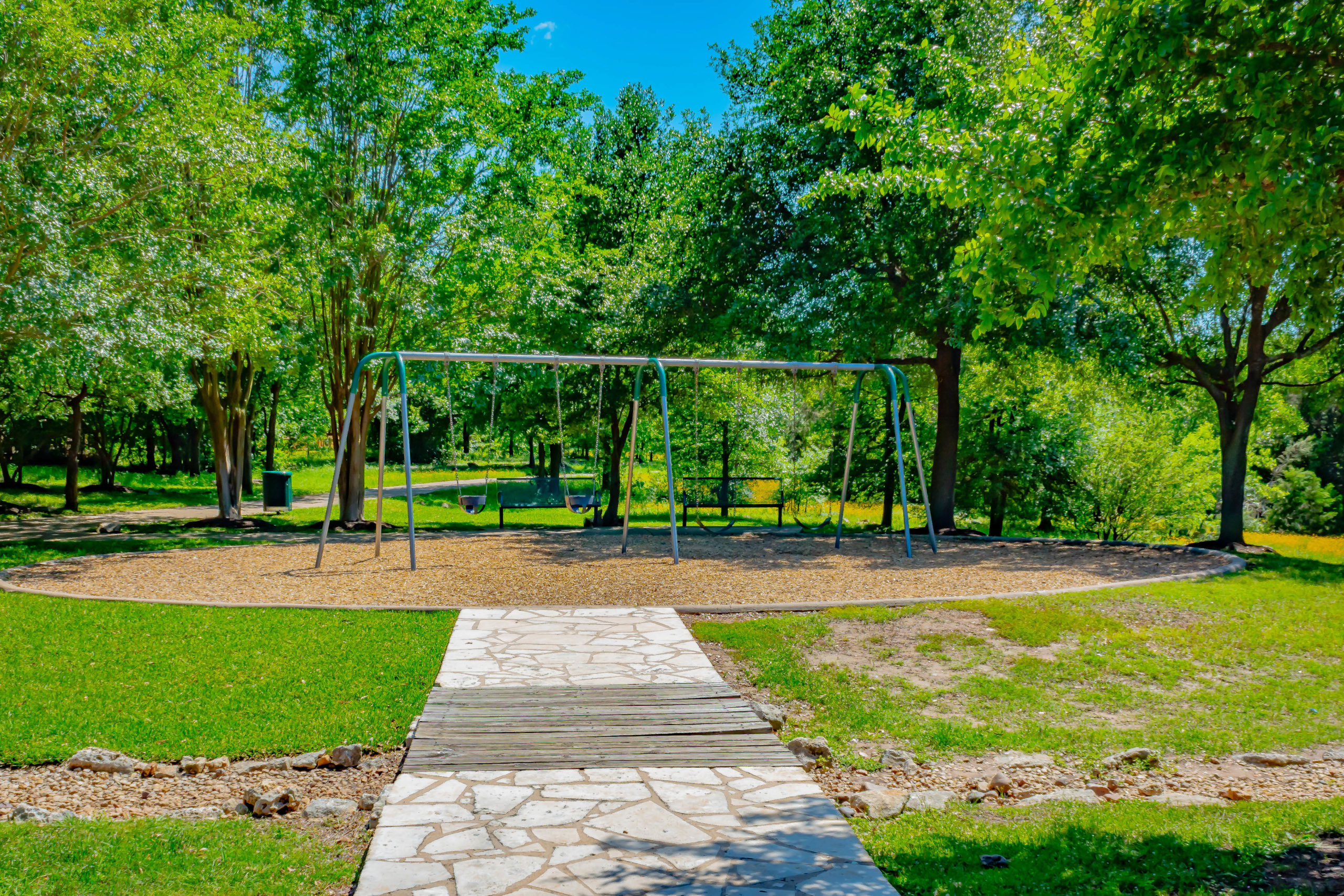 Picture of a stone path leading to a swing set.