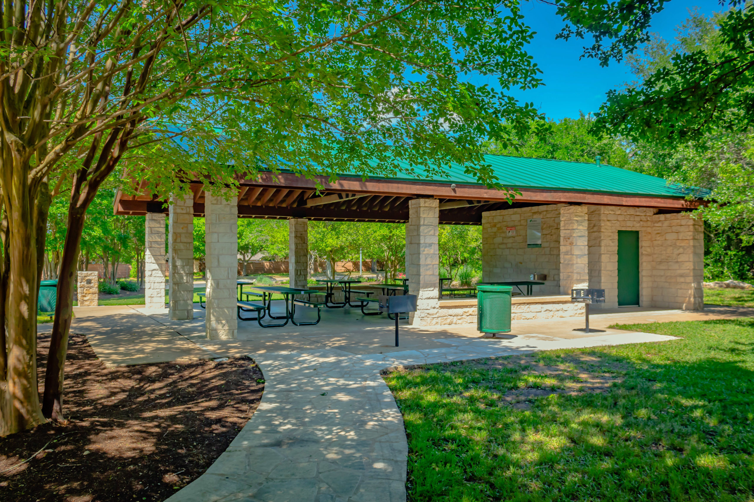 Picture of the covered pavilion and tables, surrounded by trees.