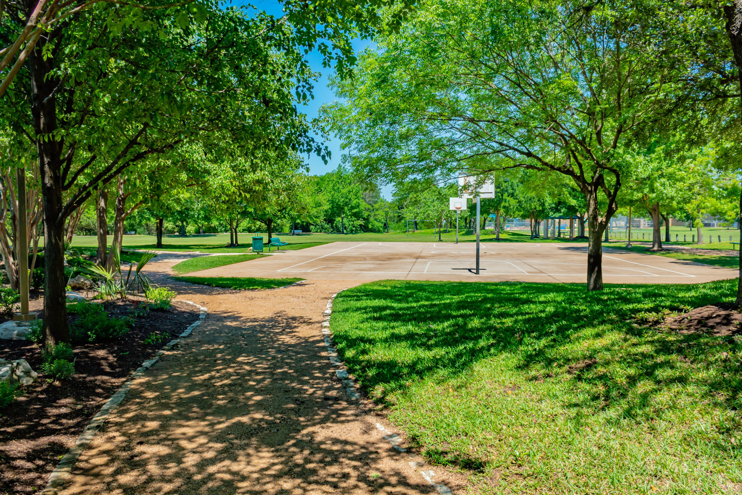 Picture of a gravel walking path leading to a basketball court.