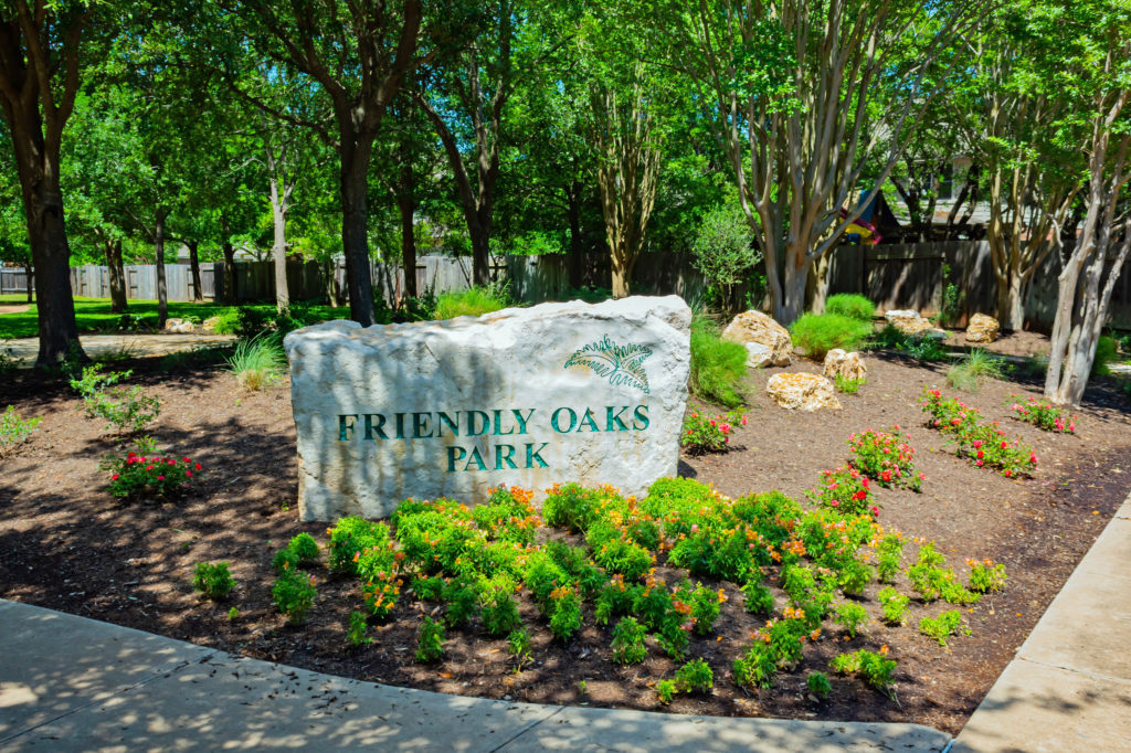 This is a picture of a large rock with the park name on it at Friendly Oaks Park.