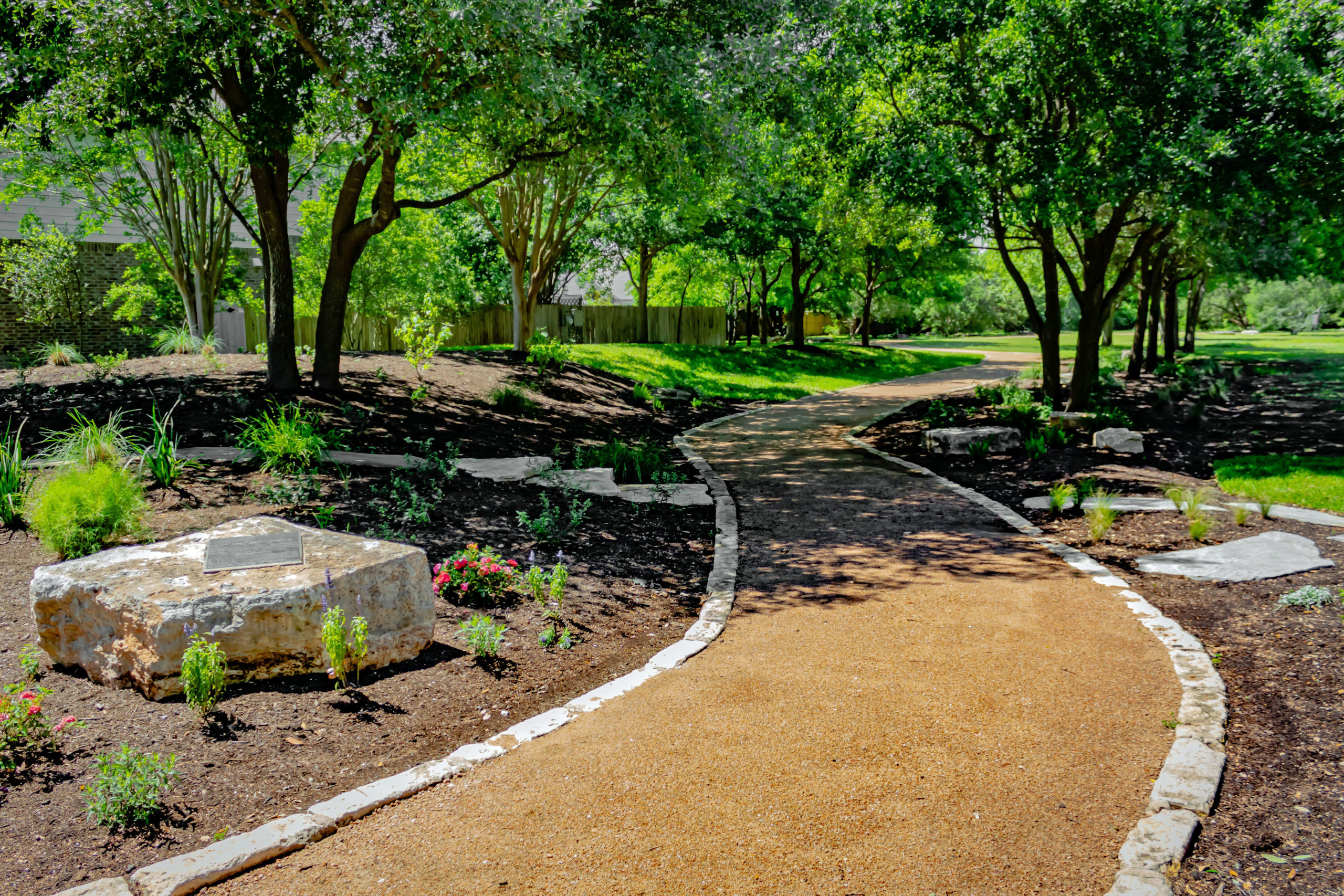 Picture of a gravel walking path among flowers and trees.