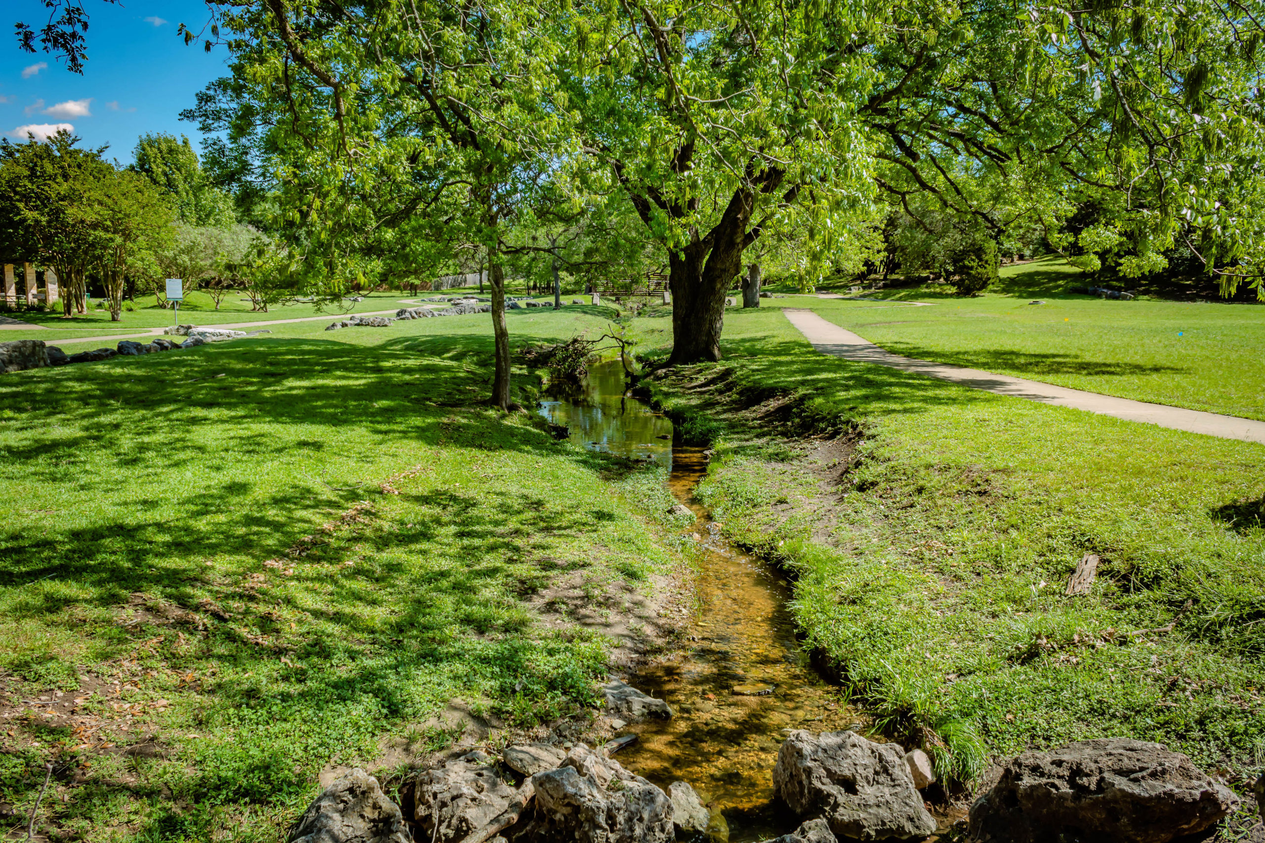 Picture of a small creek, trees, and walking path.